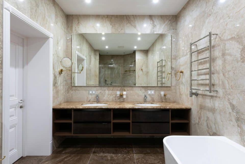 Interior of contemporary bathroom with marble walls and white clean sinks under bright glowing lamps