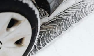A detailed view of vehicle tire tracks on a snow-covered road during winter.