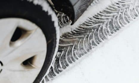 A detailed view of vehicle tire tracks on a snow-covered road during winter.