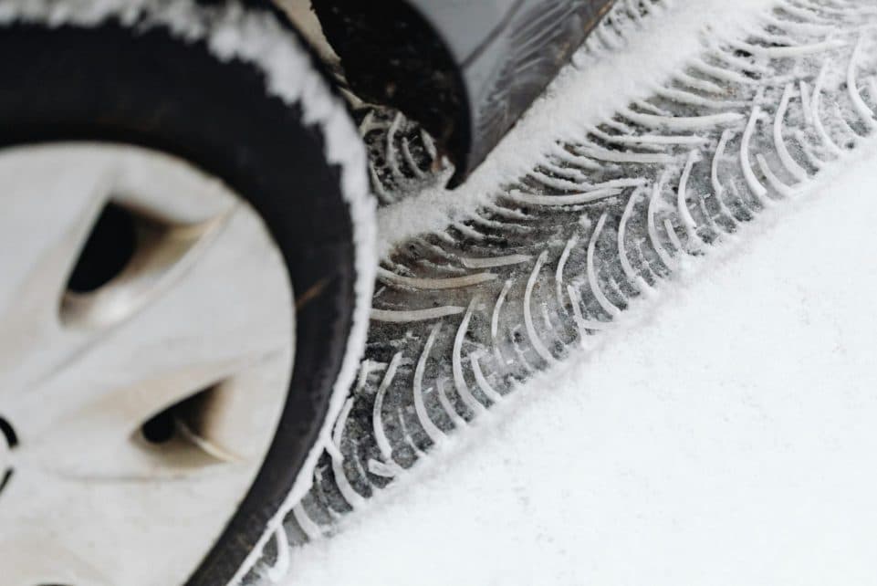 A detailed view of vehicle tire tracks on a snow-covered road during winter.
