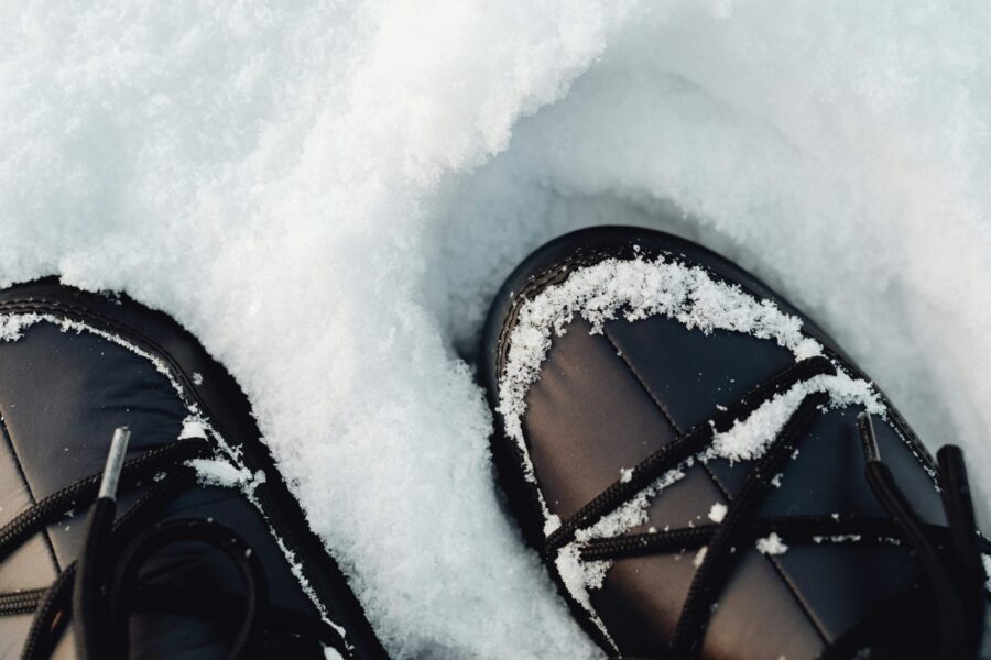 Close-up view of black winter boots covered in fresh snow.