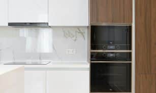 Modern interior of white and wooden kitchen with cabinets cupboards and built in appliances in contemporary flat