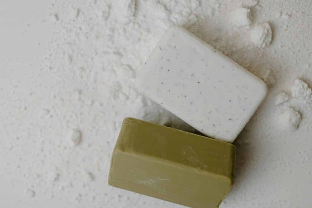 Close-up of two natural bar soaps on a white powdered surface, emphasizing hygiene.