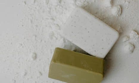 Close-up of two natural bar soaps on a white powdered surface, emphasizing hygiene.