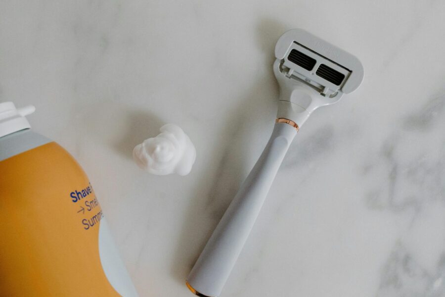 Top view of a razor and shaving foam on a marble surface, perfect for grooming and lifestyle themes.