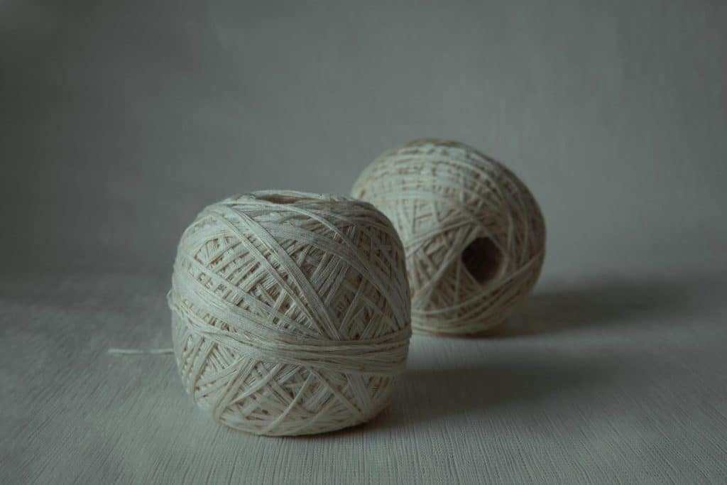 Two natural cotton yarn balls displayed in a minimalist style, ideal for arts and crafts themes.