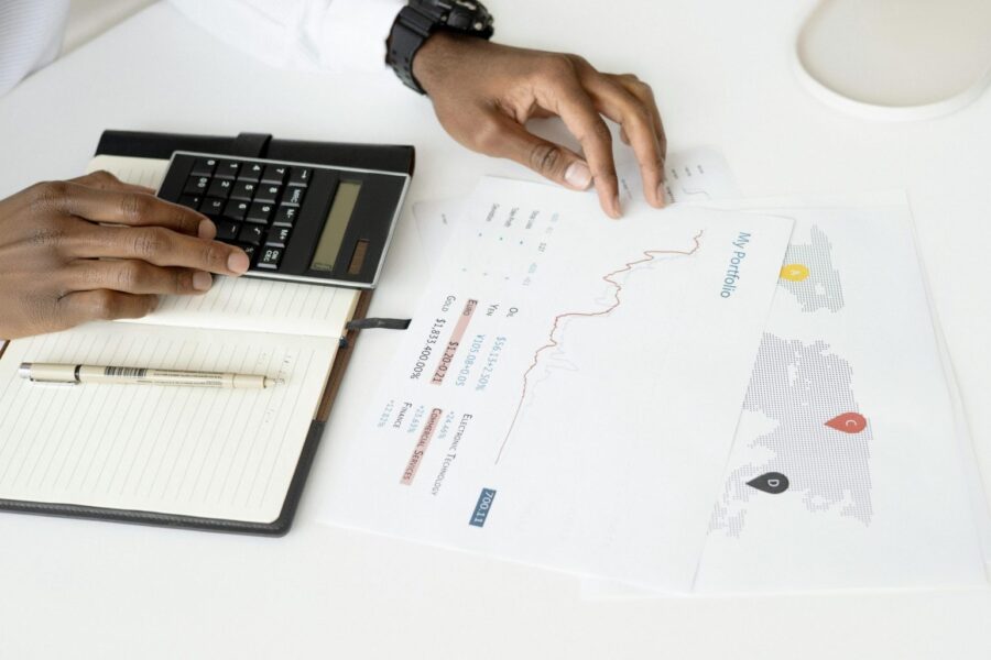 Overhead view of a person analyzing financial documents using a calculator for investment planning.