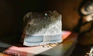A beautiful crystal stone resting on a book, illuminated by soft sunlight, creating a serene atmosphere.