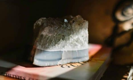 A beautiful crystal stone resting on a book, illuminated by soft sunlight, creating a serene atmosphere.