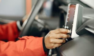 Close-up of a hand adjusting the car stereo while driving, highlighting technology and focus.