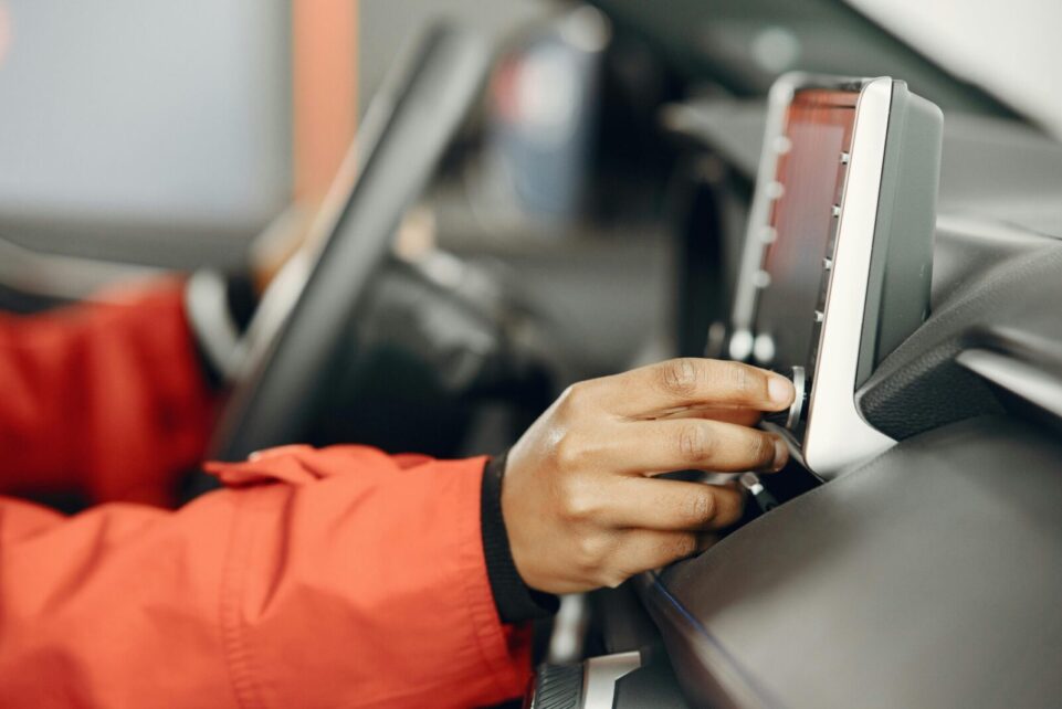 Close-up of a hand adjusting the car stereo while driving, highlighting technology and focus.