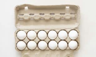 Minimalist flat lay of white eggs in a carton tray, perfect for culinary or health concepts.