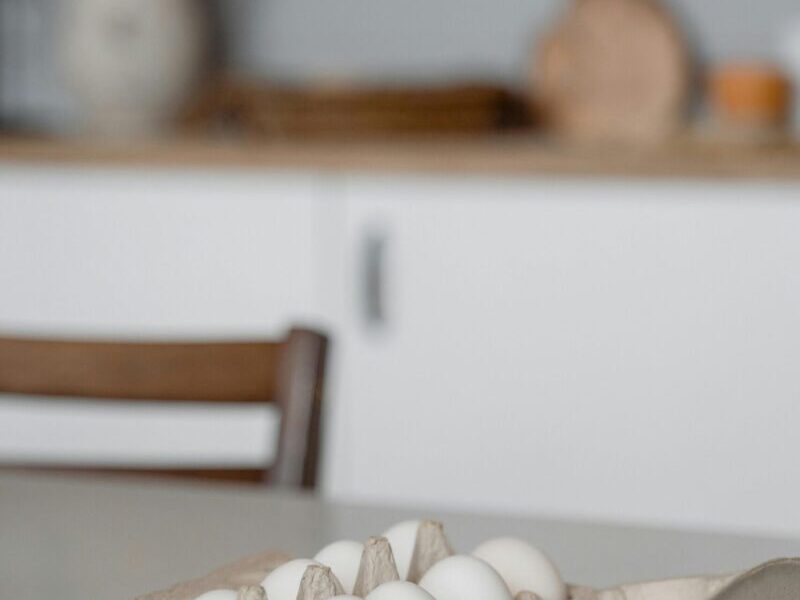 A carton of fresh eggs on a white kitchen table in a modern minimalist setting.