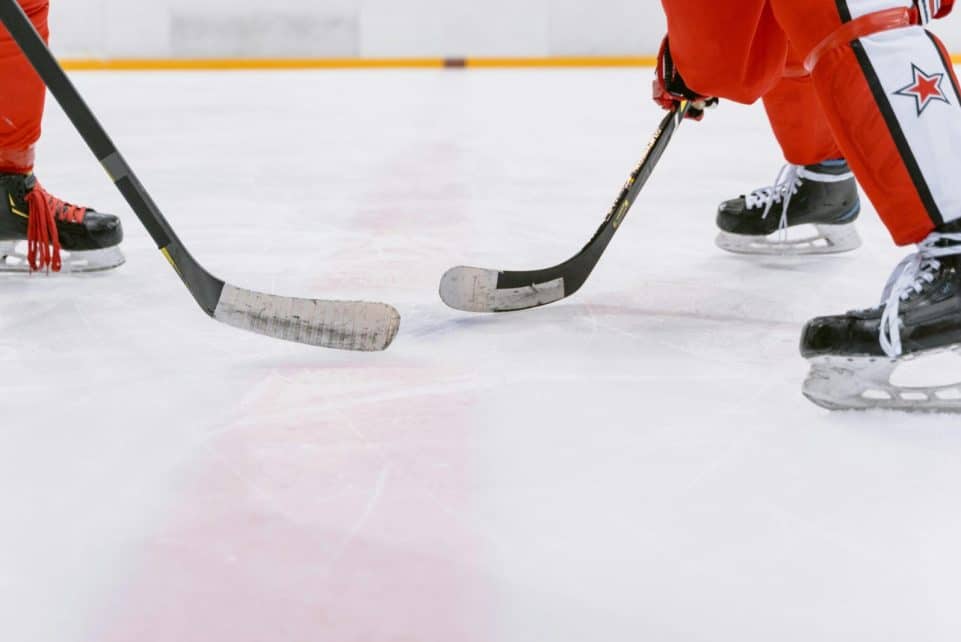 Intense close-up action of ice hockey players competing indoors, focusing on their sticks and skates.