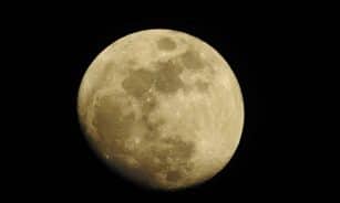 Detailed photograph of a full moon set against a dark night sky, highlighting lunar features.