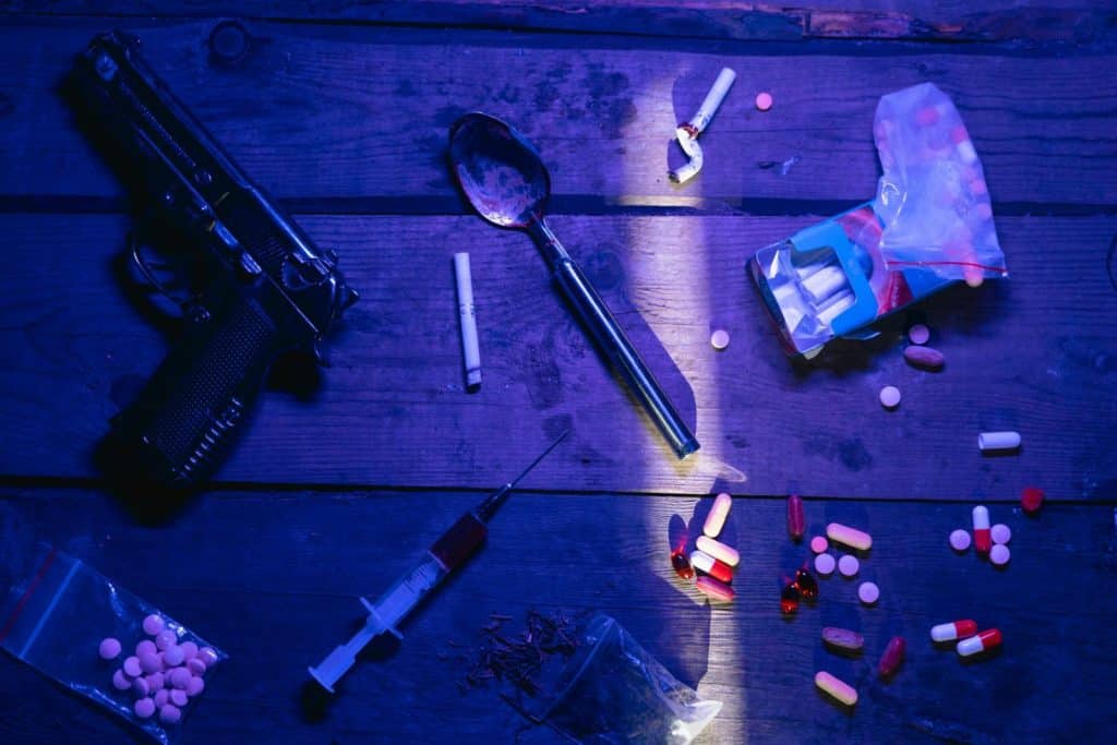 Intriguing still life image depicting pills, a gun, and syringe under dramatic lighting.