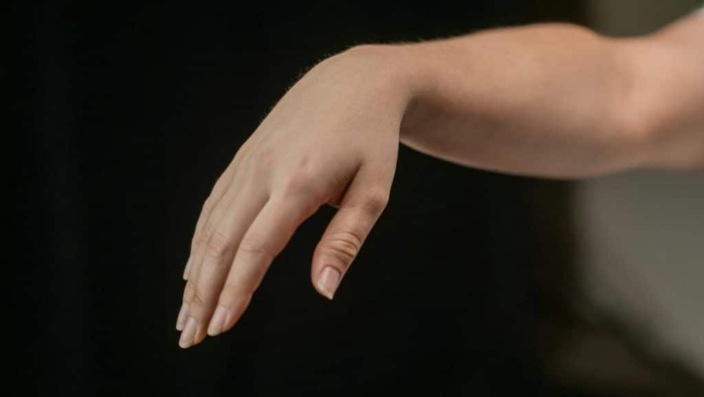 Close-up of a human hand in soft focus, highlighting delicate fingers and fingernails.