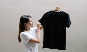 Side view of positive female wearing casual outfit standing with black shirt against gray background