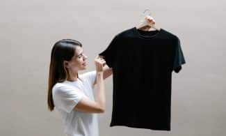 Side view of positive female wearing casual outfit standing with black shirt against gray background