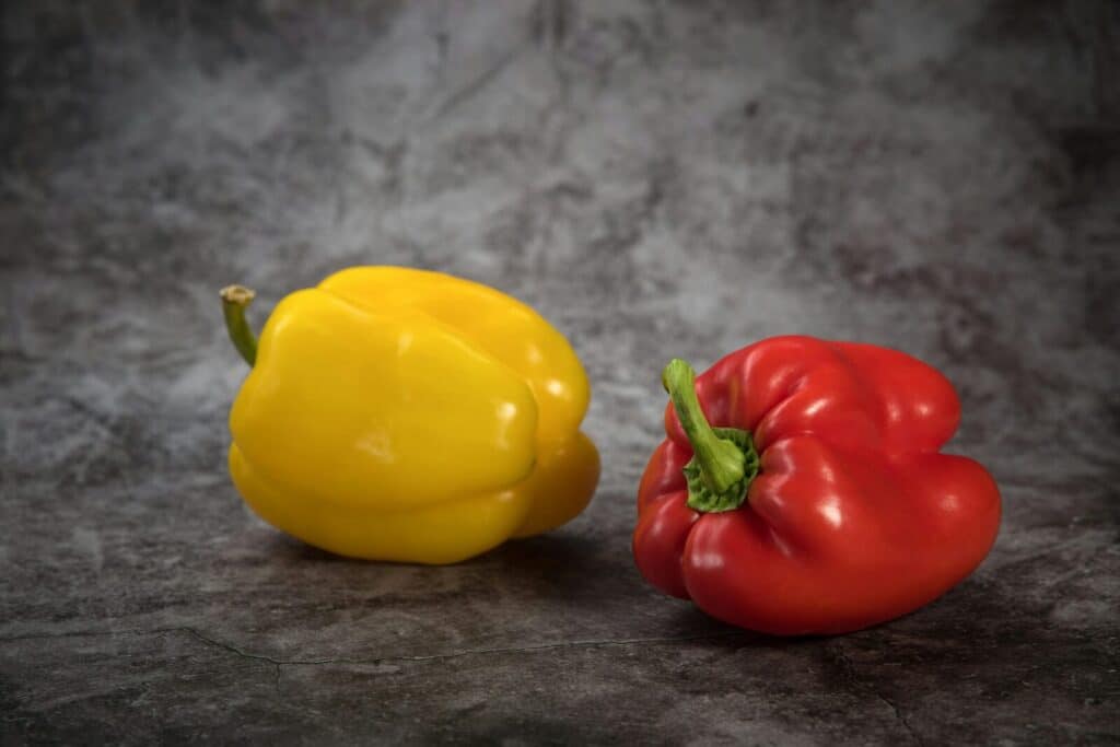 Close-up of fresh red and yellow bell peppers on a gray surface. Perfect for healthy food concepts.