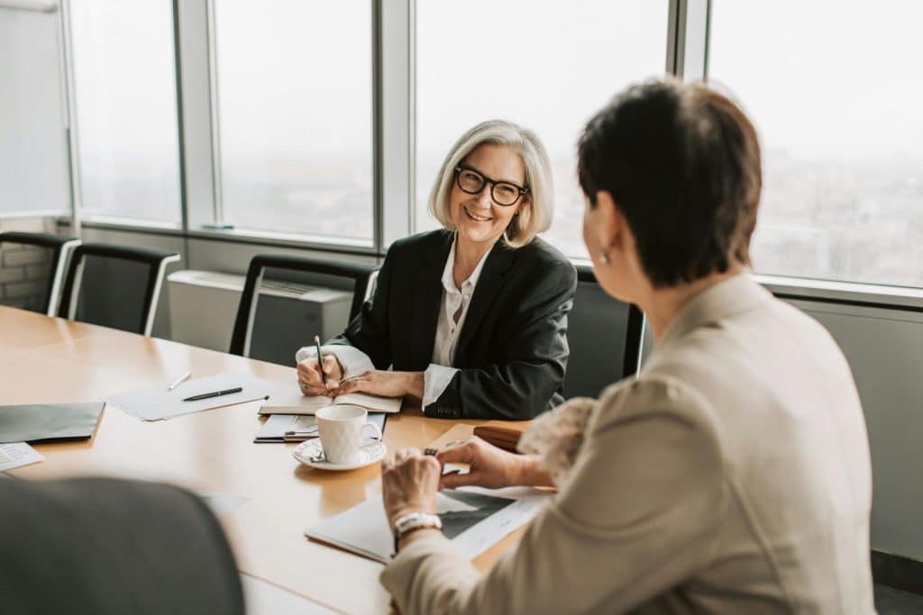 Two businesswomen in discussion during a meeting in a modern office setting.