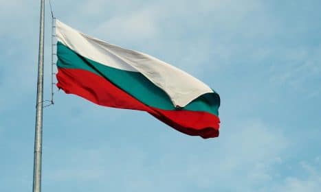The national flag of Bulgaria waving on a flagpole against a clear blue sky in Varna.