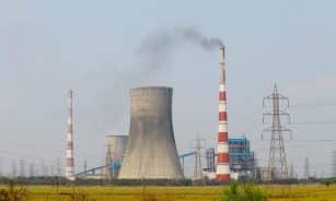 Aerial view of an industrial power plant in Vijayawada, India, with cooling towers and chimneys emitting smoke.