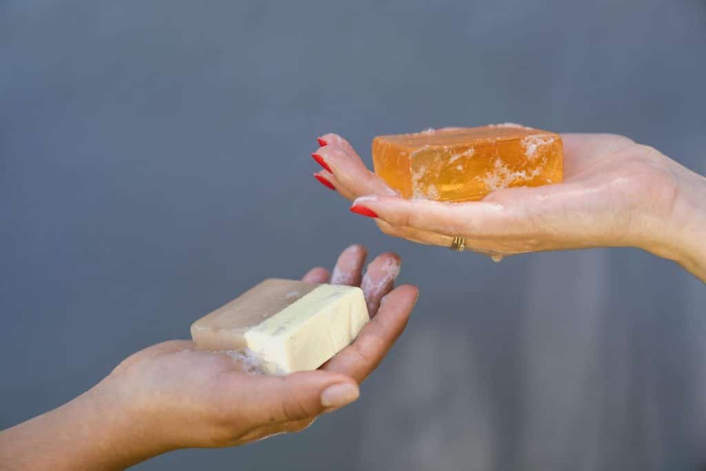 Close-up of hands holding different soap bars emphasizing personal hygiene and cleanliness.