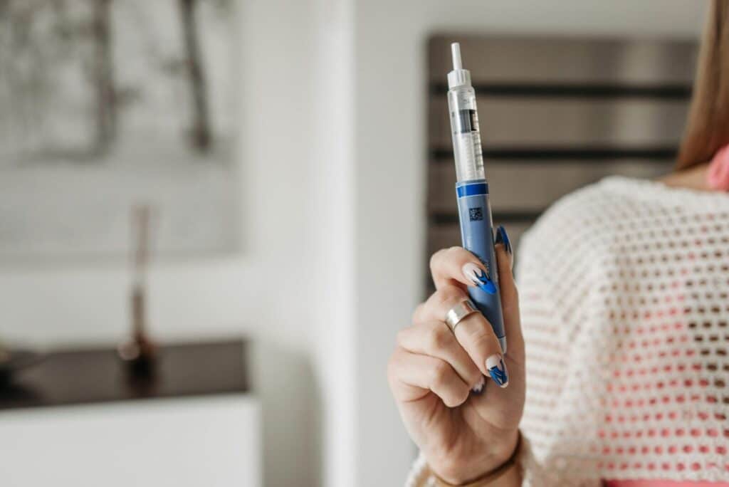 Woman holding an insulin pen, showcasing healthcare and diabetes management in a modern setting.