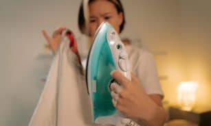 Asian woman ironing indoors experiencing an ironing fail with a burned garment. Captures frustration.