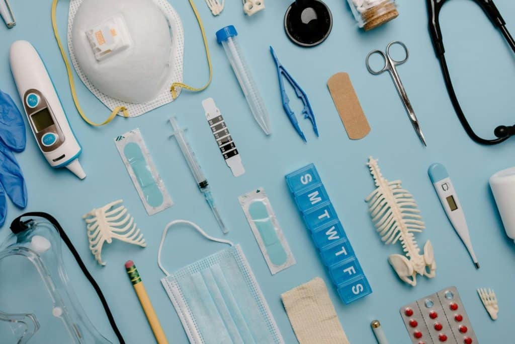 A comprehensive flat lay of diverse medical supplies including PPE and diagnostic equipment on a blue surface.