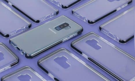 Close-up of a Samsung phone surrounded by transparent cases on a purple surface, showcasing modern technology.