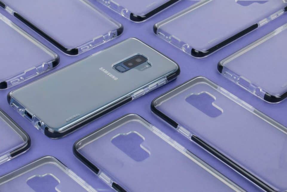 Close-up of a Samsung phone surrounded by transparent cases on a purple surface, showcasing modern technology.