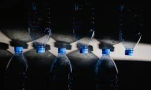 Artistic arrangement of plastic water bottles casting shadows, emphasizing sustainability.