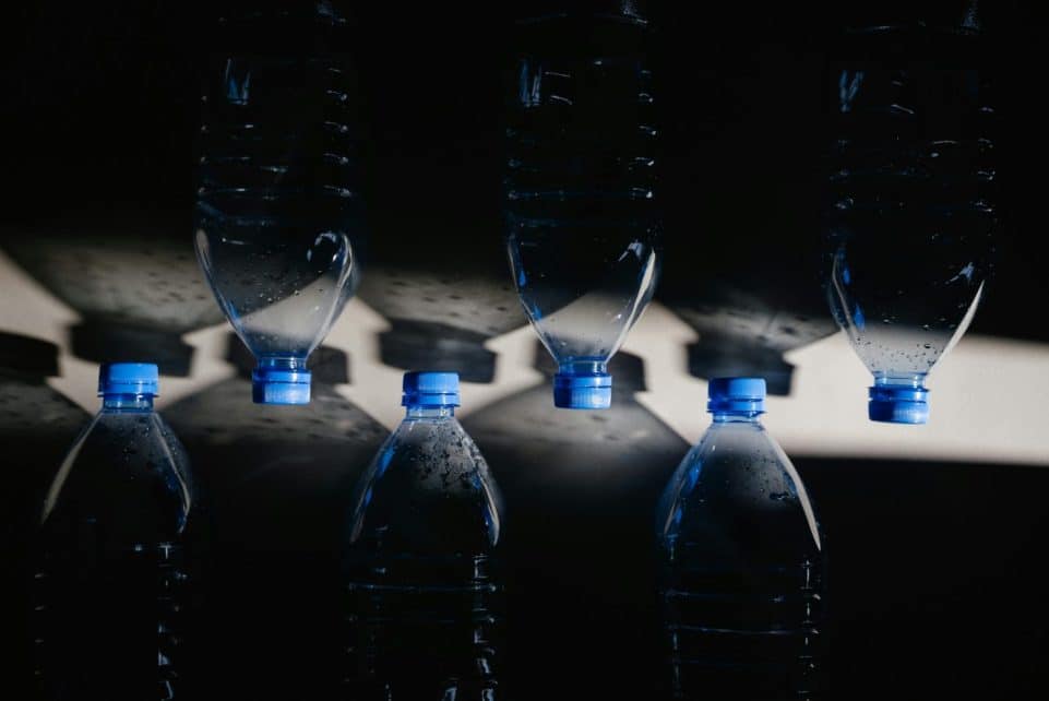 Artistic arrangement of plastic water bottles casting shadows, emphasizing sustainability.