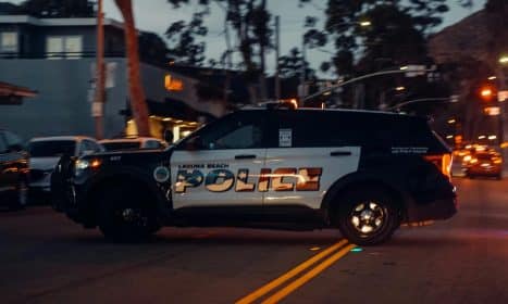 Laguna Beach police vehicle patrols the street at night, showcasing law enforcement presence.