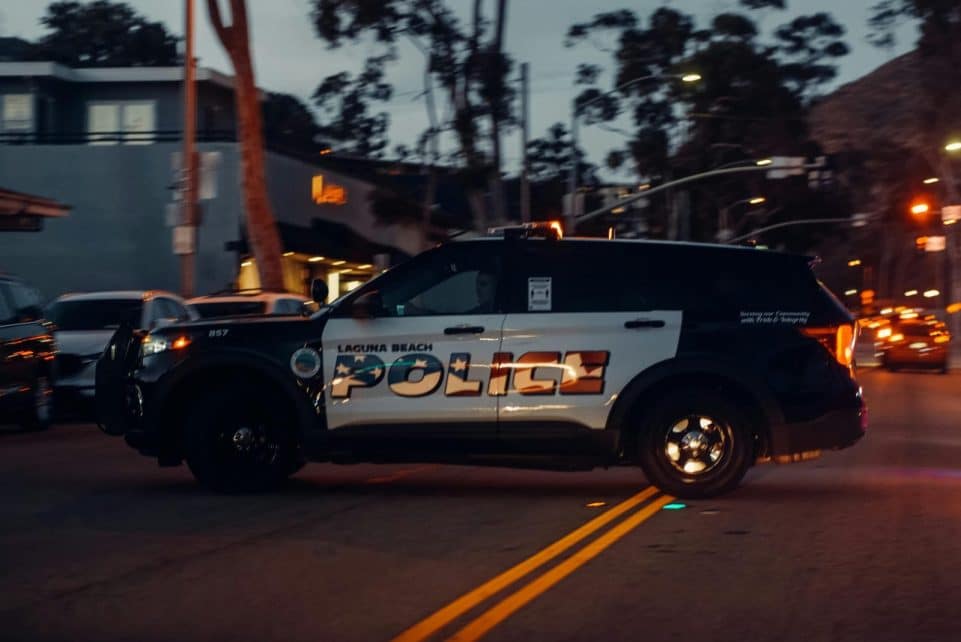 Laguna Beach police vehicle patrols the street at night, showcasing law enforcement presence.