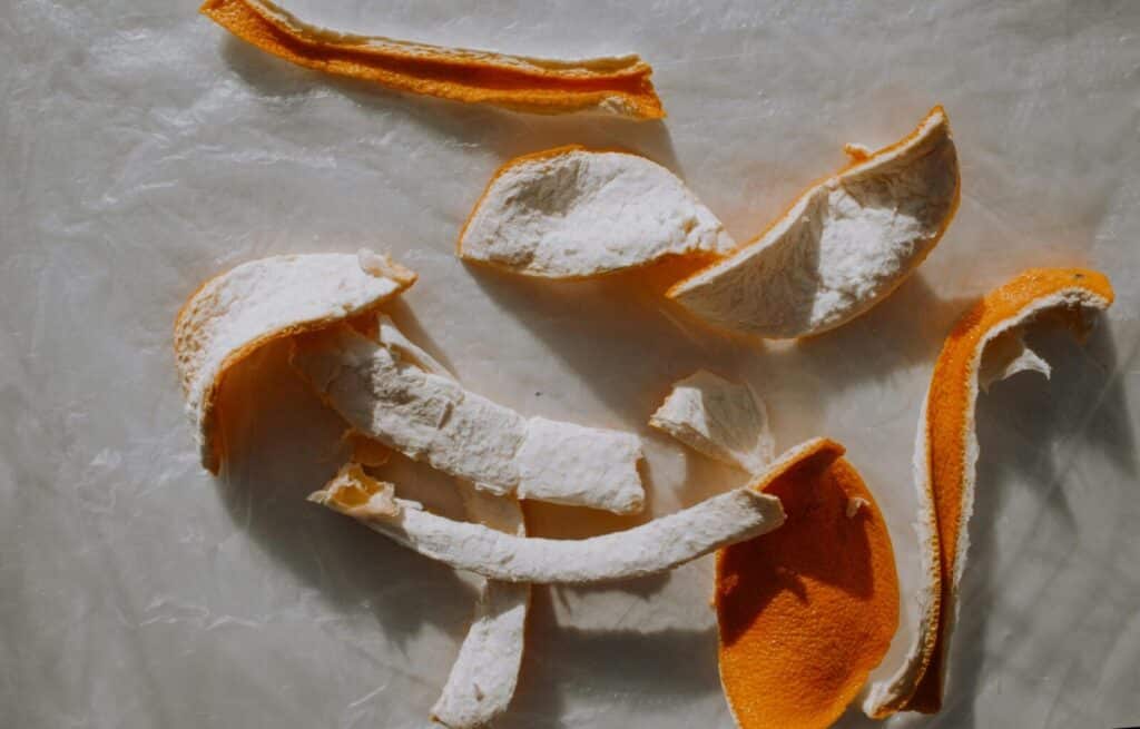 A top view of dried orange peels scattered on parchment paper, perfect for natural textures.