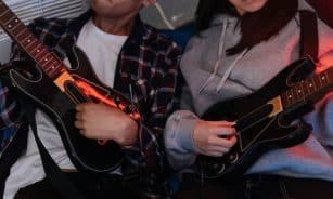 Two friends enjoying Guitar Hero game session, focusing on teamwork and fun.