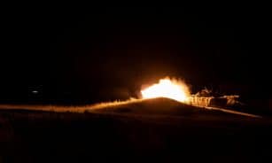 A powerful fireball eruption during nighttime military training creates a dramatic scene.
