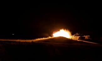 A powerful fireball eruption during nighttime military training creates a dramatic scene.