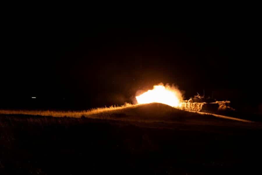 A powerful fireball eruption during nighttime military training creates a dramatic scene.