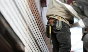 Close-up of a construction worker with hammer and tools, focused on the job.