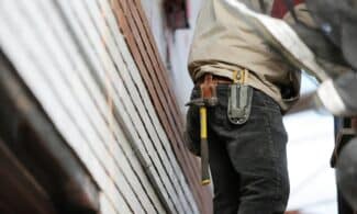 Close-up of a construction worker with hammer and tools, focused on the job.