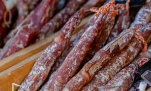 A detailed close-up of traditional Italian salami sticks arranged in rows, showcasing their texture.