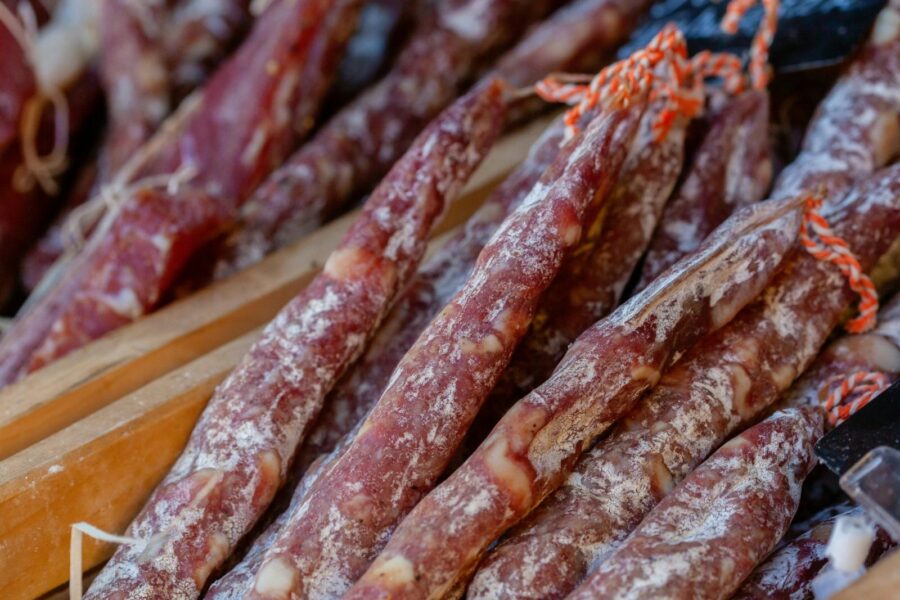 A detailed close-up of traditional Italian salami sticks arranged in rows, showcasing their texture.