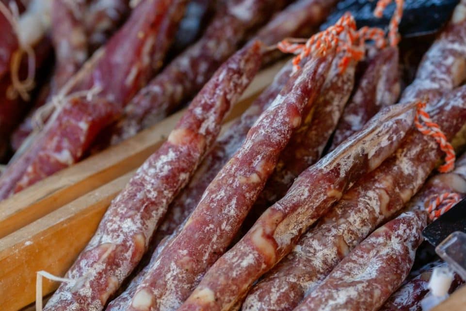 A detailed close-up of traditional Italian salami sticks arranged in rows, showcasing their texture.