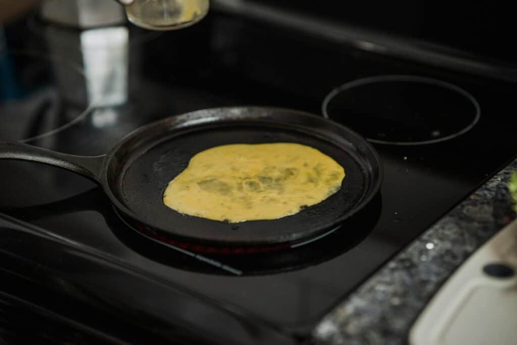 A close-up of scrambled eggs cooking in a pan on an induction stove.