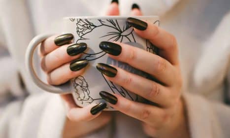 A close-up of manicured hands holding a decorative mug, perfect for lifestyle and coffee themes.