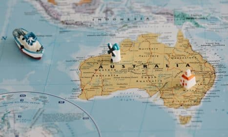 Miniature windmill and ship placed atop a map of Australia, highlighting travel concepts.